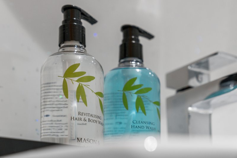 Bathroom counter with two branded pump bottles and chrome fixtures