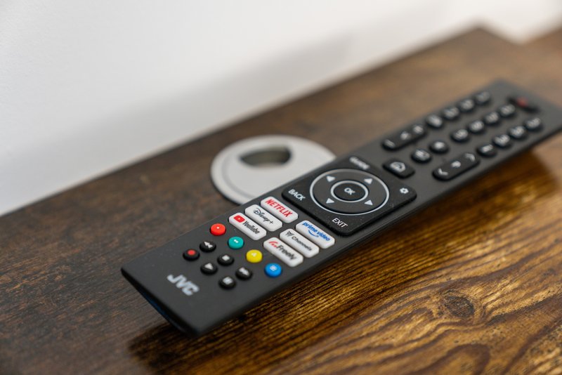 Remote control with streaming app buttons on wooden surface