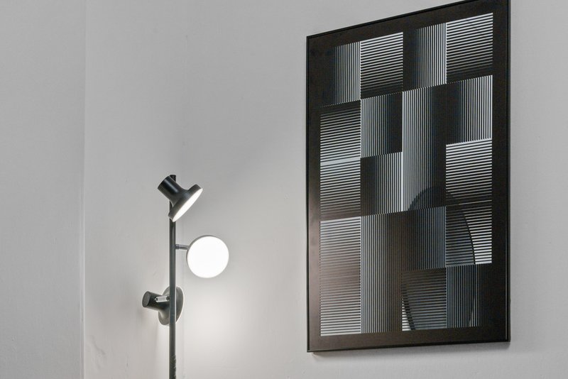 Minimalist bathroom with black shower head fixture, round mirror and geometric window blind wall art