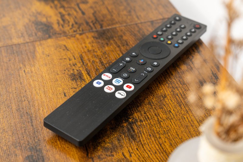 Remote control lying on wooden table with blurred background