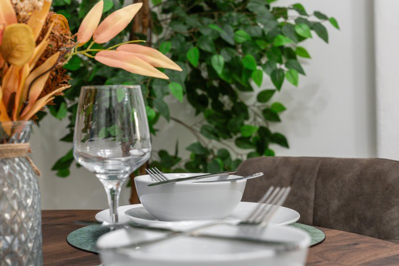 Dining table setting with white dishes, wine glass, and fresh flower arrangement