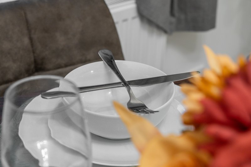 Place setting with white plates, spoons, and colorful flowers in foreground