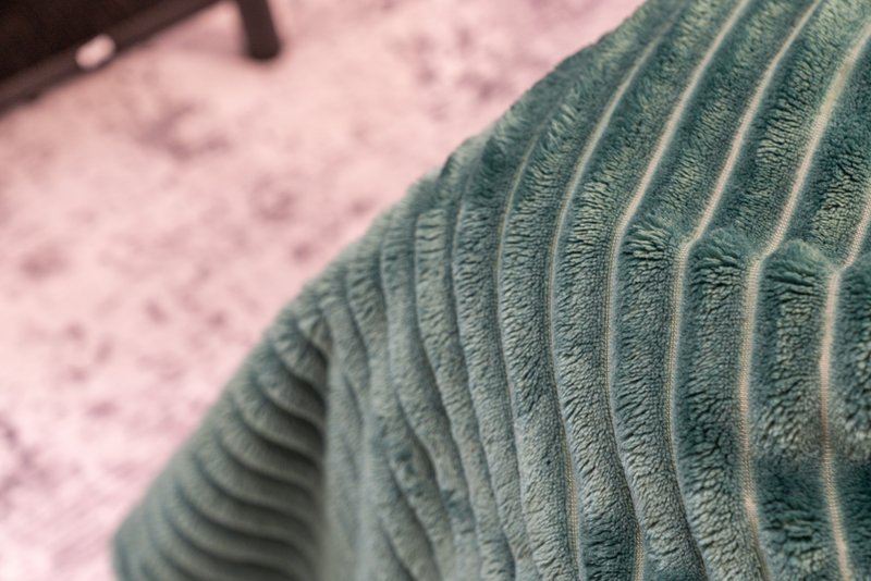 Close-up detail of green textured fabric or cushion with ribbed pattern