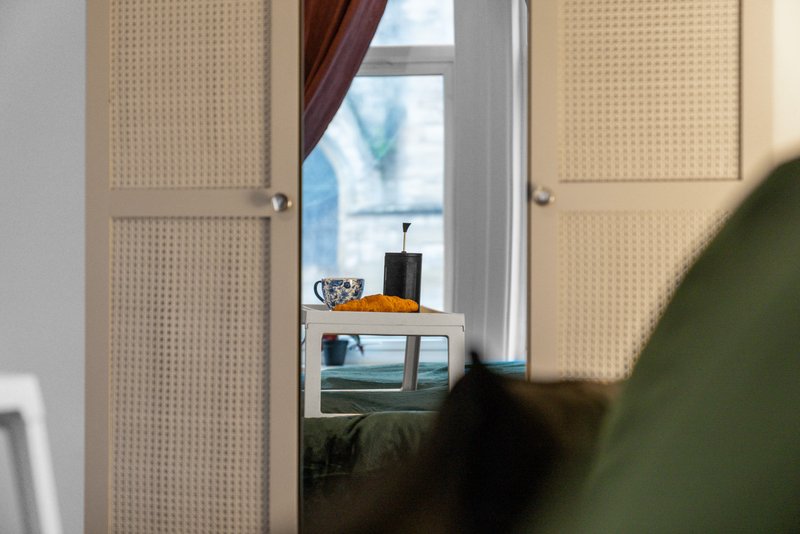Hallway with perforated doors, window with curtains, and decorative items on shelf