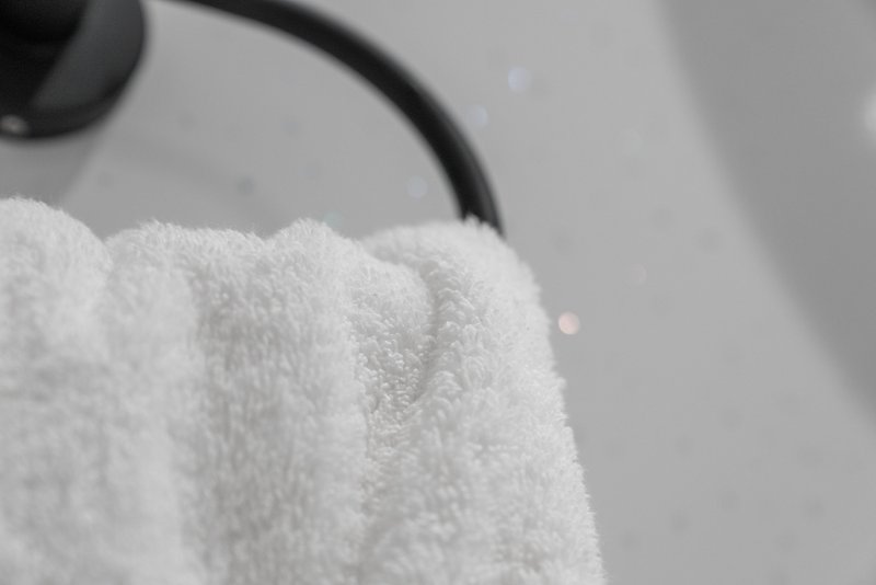 Close-up of white fluffy towel draped over bathroom rack