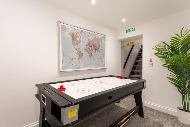 Recreation room with air hockey table, world map poster, and potted plant