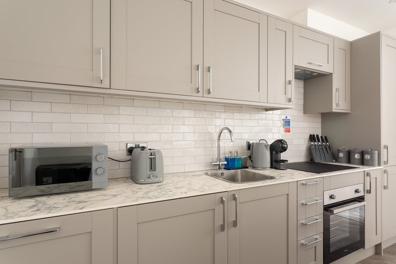 Modern kitchen with cream cabinetry, marble countertop, subway tile backsplash, and integrated appliances