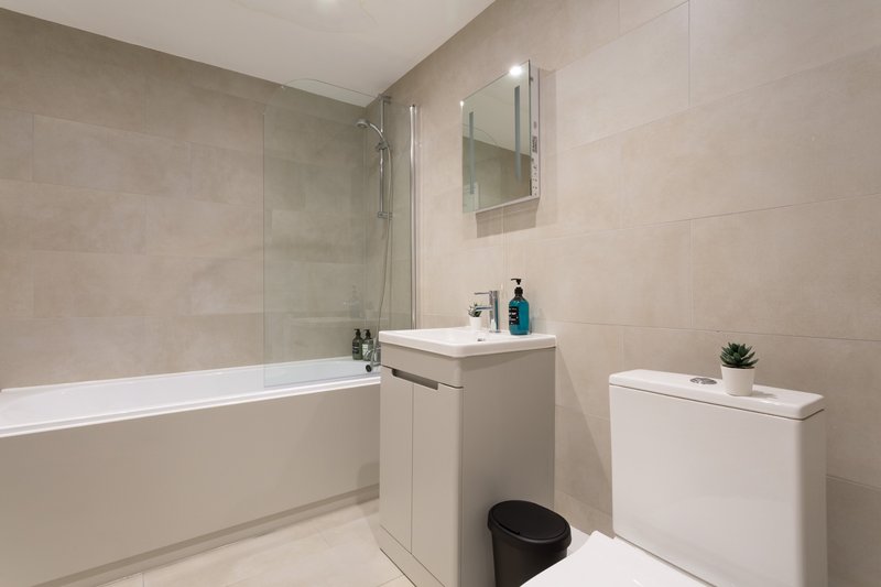 Modern bathroom with bathtub, sink vanity, mirror, toilet and tiled walls