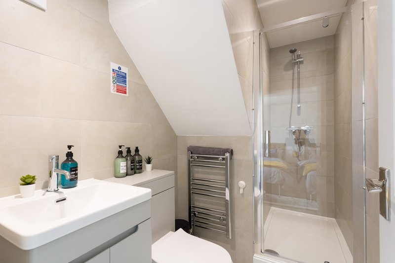 Modern bathroom with white sink, shower enclosure, towel rail and skylight window