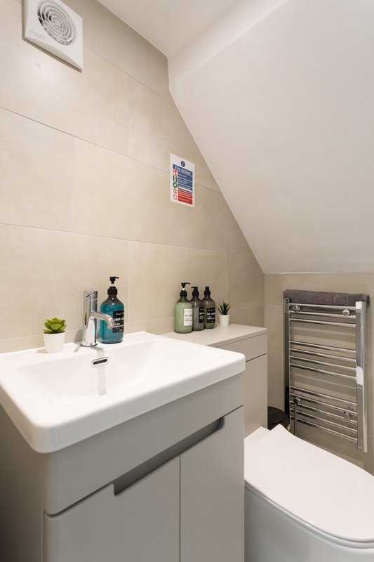Modern bathroom with white vanity sink, toiletries, heated towel rail and toilet