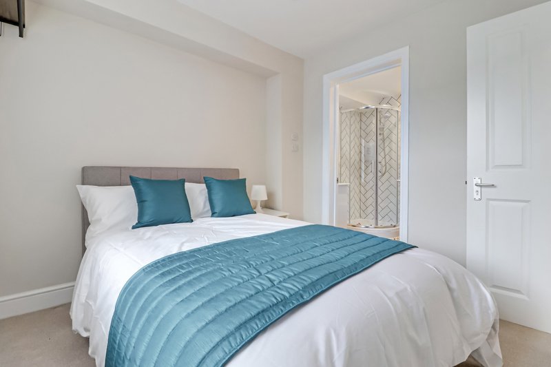 Bright bedroom with double bed, teal bedding, grey headboard and wardrobe