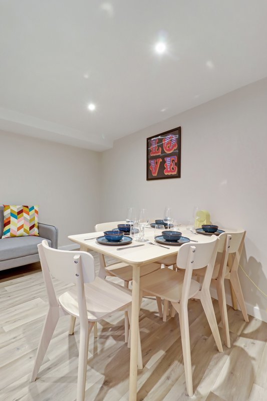 Modern dining area with light wood table, white chairs, place settings and wall art