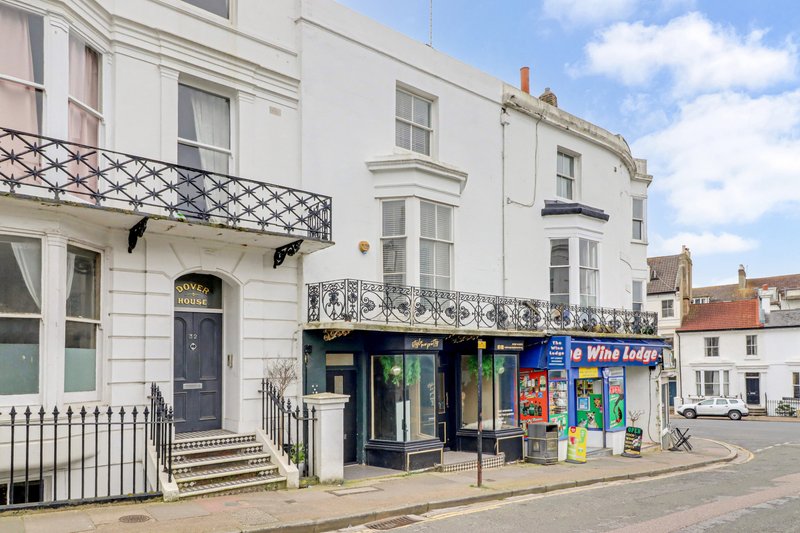 White Georgian townhouse with ground-floor shop frontage on residential street