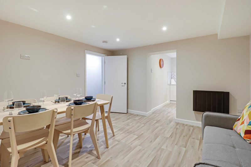 Open-plan living space with dining table, chairs, sofa, and kitchen area
