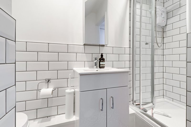 Modern bathroom with white subway tiles, gray vanity, mirror, and shower enclosure
