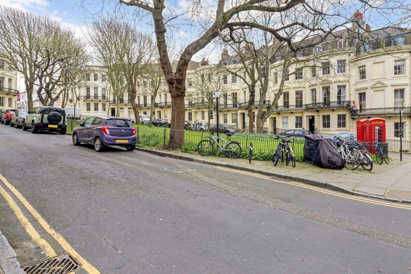 Tree-lined London street with parked cars, bicycles, and period townhouses