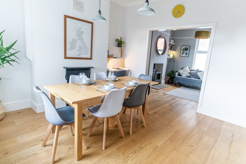Open-plan dining and living area with wooden table, mixed chairs, and hardwood flooring