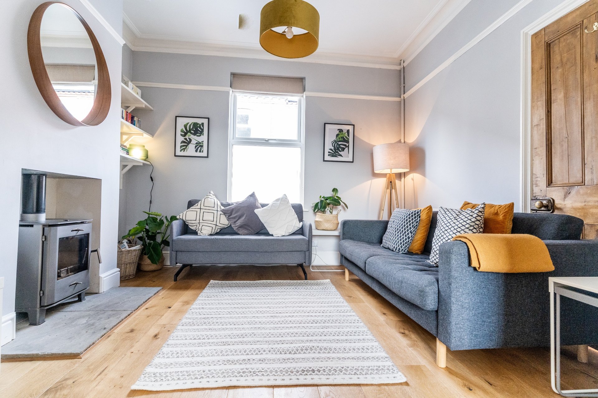 Bright living room with blue sofas, wooden floor, fireplace and gold pendant light