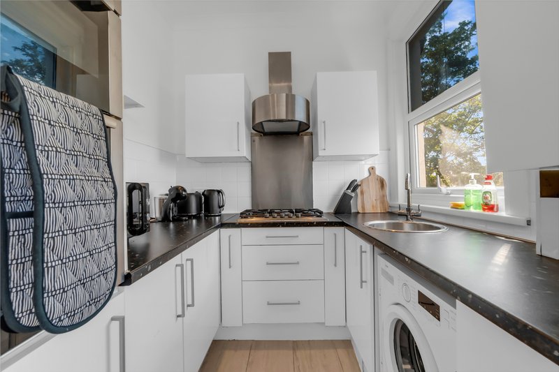 Modern white kitchen with black countertops, stainless steel appliances and window view