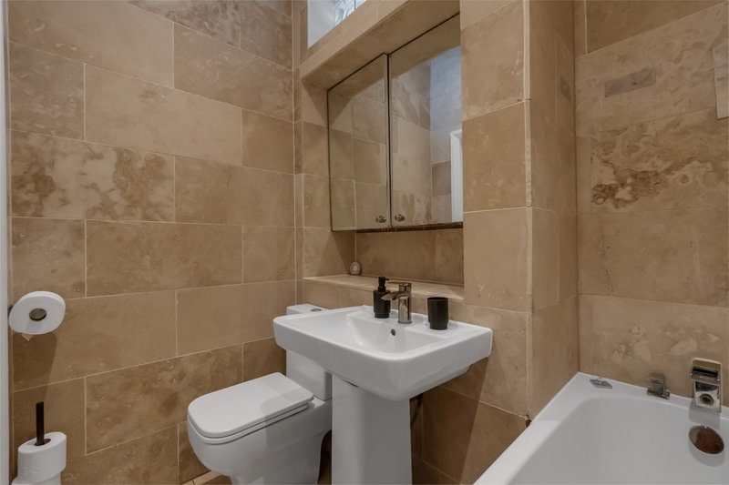 Bathroom with pedestal sink, toilet, bathtub and mirrored cabinet