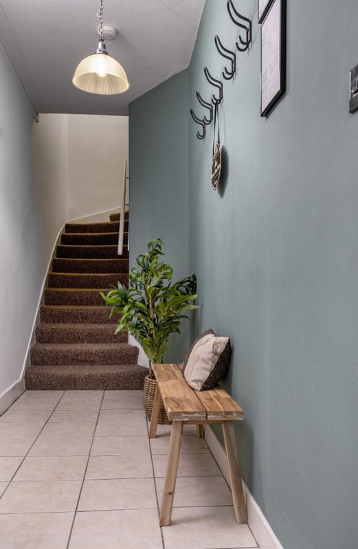 Hallway with wooden staircase, pendant light, wooden bench, potted plant and cushion