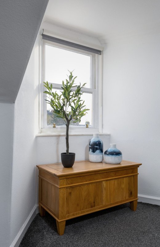Bright corner with wooden chest, potted tree, blue ceramic vessels and window
