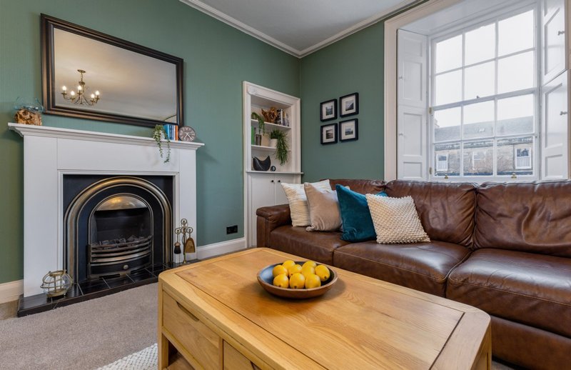 Living room with fireplace, leather sofa, wooden coffee table and large window