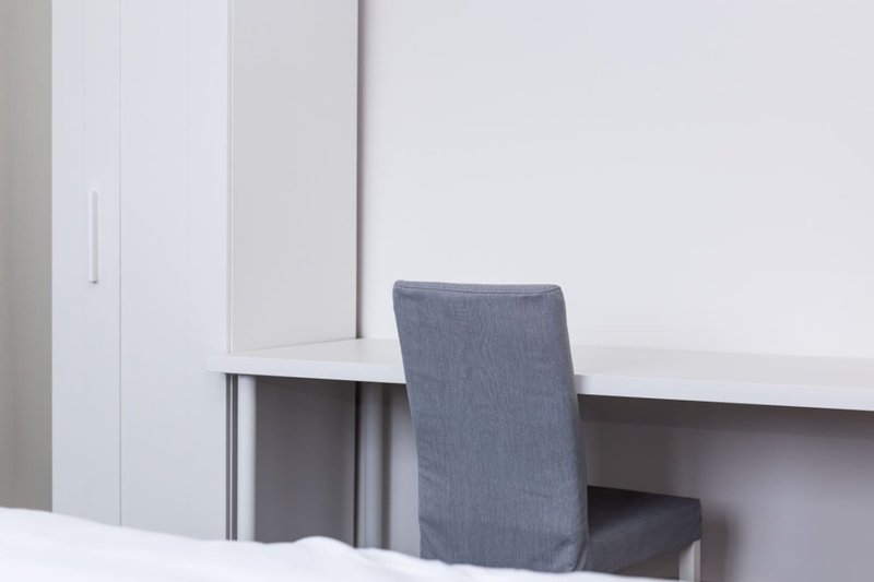 Modern home office with white built-in storage, desk, and gray upholstered chair