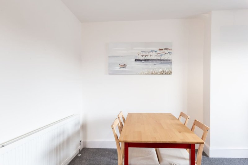 Dining room with wooden table, chairs, white radiator and ship artwork
