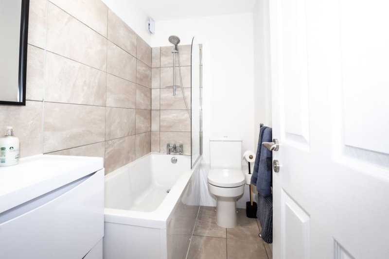 Modern bathroom with white vanity, tiled shower enclosure, toilet and heated towel rail