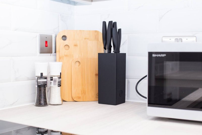 Kitchen counter with microwave, knife block, cutting board, and seasoning containers