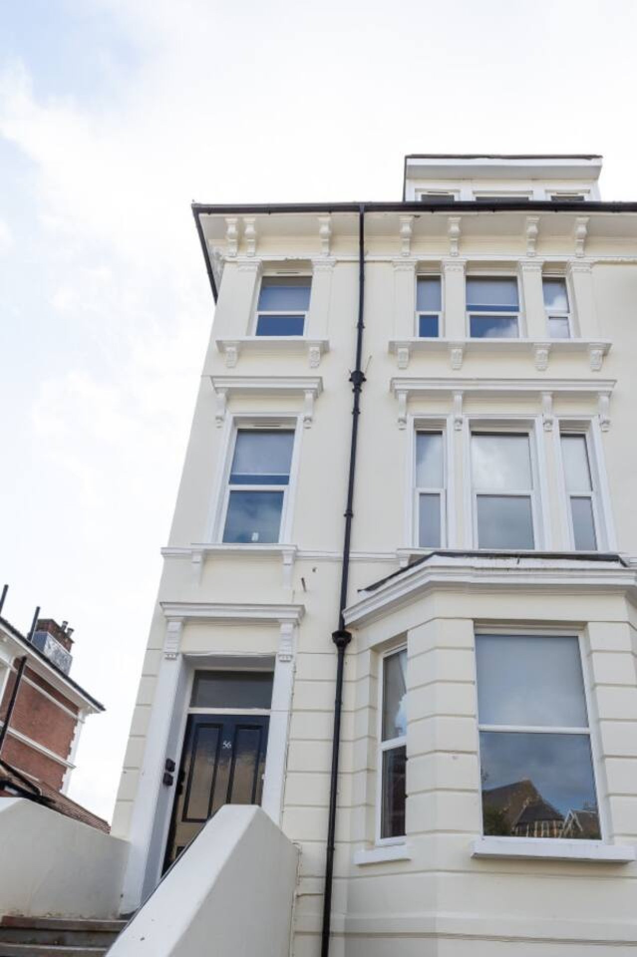 White Victorian townhouse exterior with multiple sash windows and dark downpipes