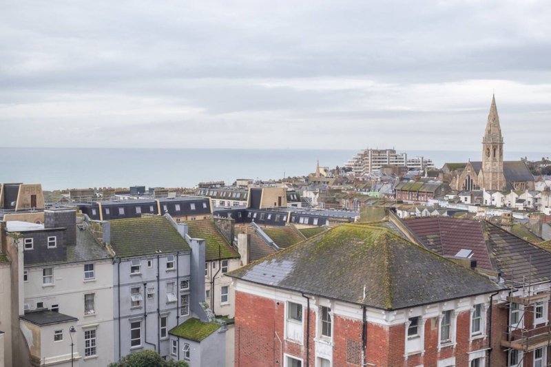 Elevated coastal town view with residential buildings, church spire, and sea horizon