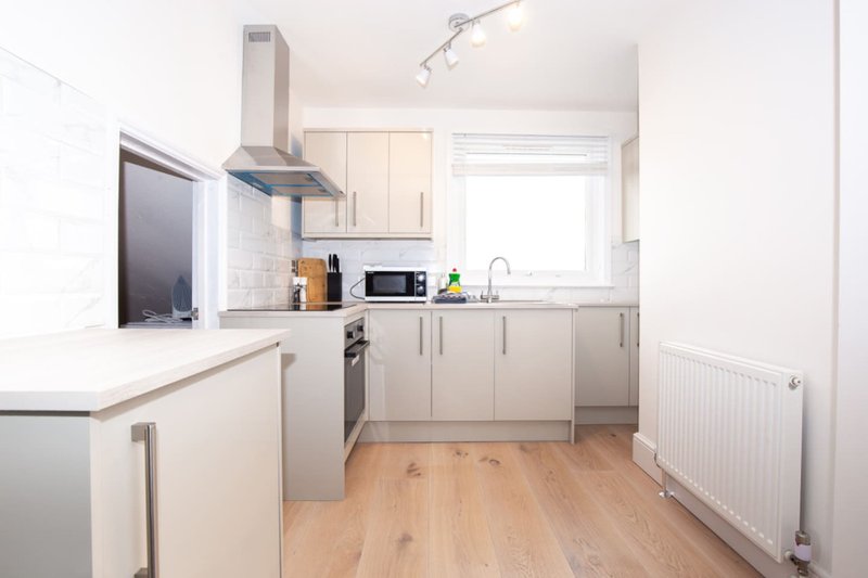 Modern kitchen with cream cabinets, stainless steel appliances, wooden flooring and window
