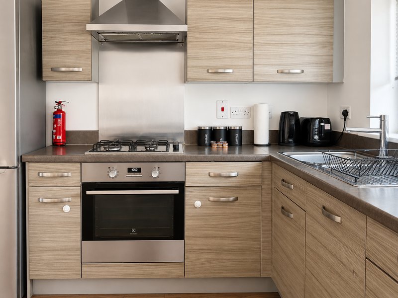 Modern kitchen with wooden cabinets, gas hob, oven and stainless steel appliances