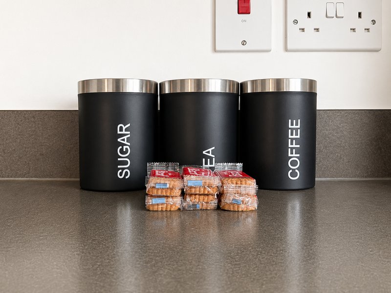 Kitchen counter with three black labeled storage canisters and complimentary snacks
