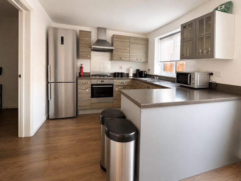 Modern kitchen with wood cabinetry, stainless steel appliances, island counter and breakfast bar