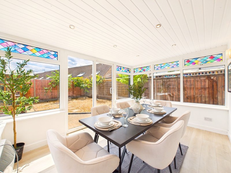 Modern dining room with black table, cream chairs, potted plant and garden views
