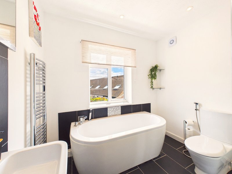 Modern bathroom with freestanding white bathtub, toilet, sink and heated towel rail