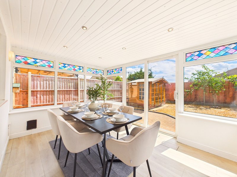 Bright dining room with table, chairs, and large windows overlooking garden