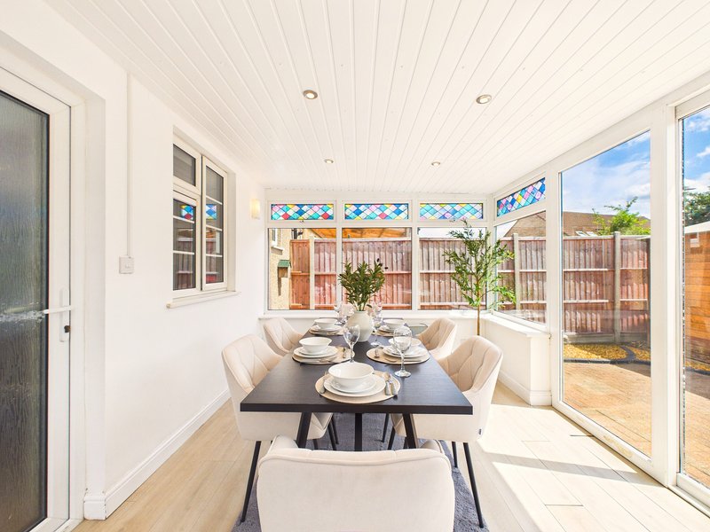 Bright dining room with black table, beige chairs, and large windows overlooking garden