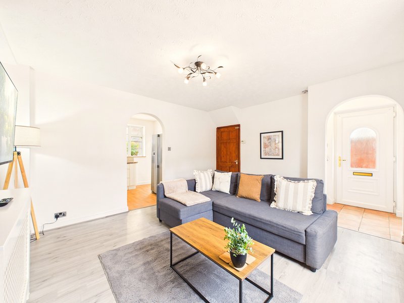 Bright living room with grey sectional sofa, wooden coffee table, and access to multiple rooms