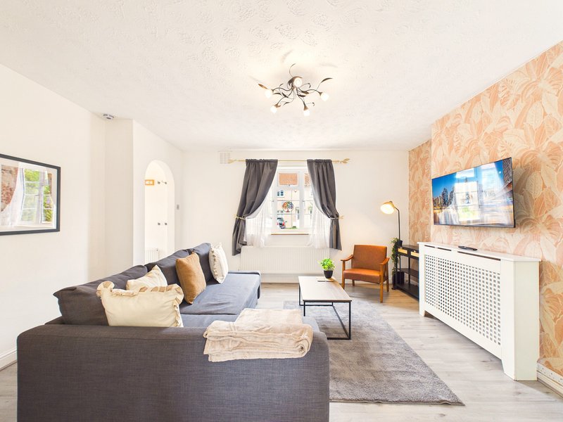 Bright living room with grey sofa, orange armchair, TV, and patterned wallpaper