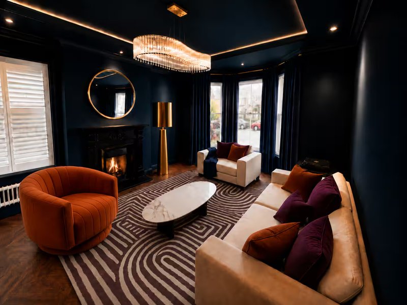 Luxurious living room with dark blue walls, fireplace, orange velvet armchair, beige sofa, and chandelier
