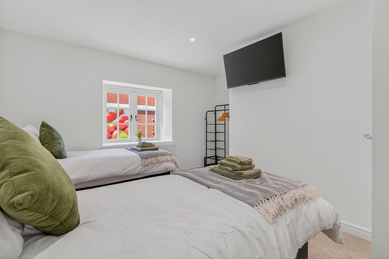 Comfortable twin bedroom with two separate single beds, ideal for contractors sharing the property. Includes wall-mounted Smart TV and storage, perfect for longer stays.