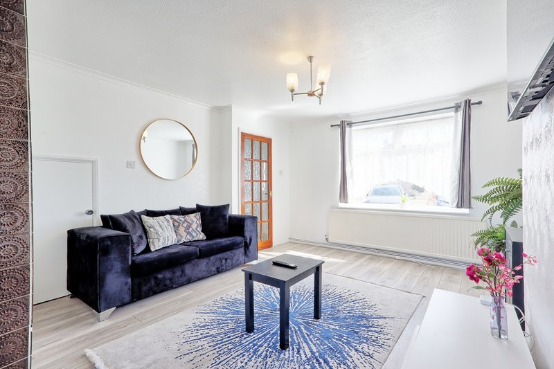 Bright living room with navy velvet sofa, blue rug, round mirror and large windows