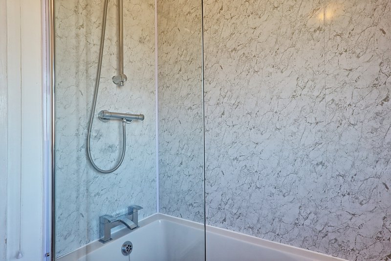 Modern bathroom with marble-tiled shower enclosure, rainfall showerhead and white bathtub