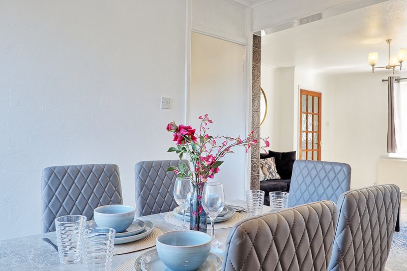 Modern dining room with upholstered chairs, table set with flowers and tableware