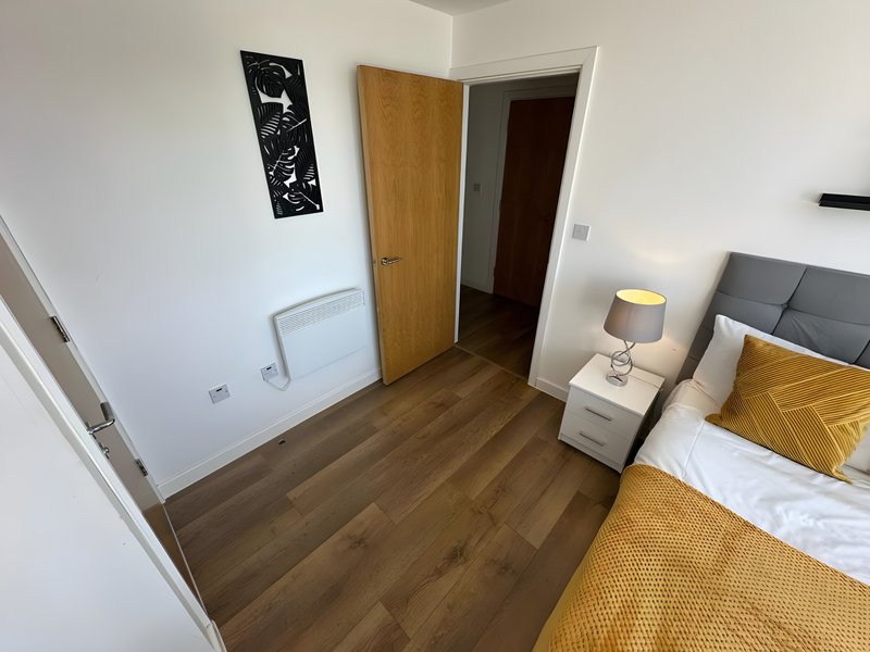 Bedroom with double bed, wooden floor, bedside lamp and wall art