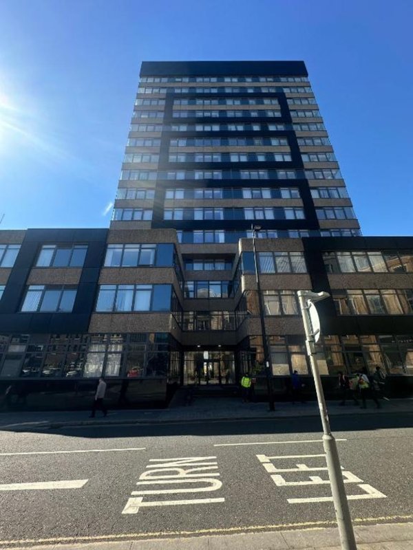 Modern residential apartment building with street-level shops and clear sky